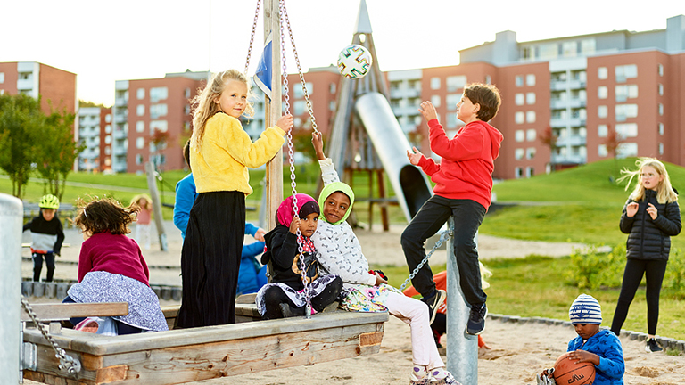 Områdesbild från Nacksta med lekande barn i en lekpark. Foto.