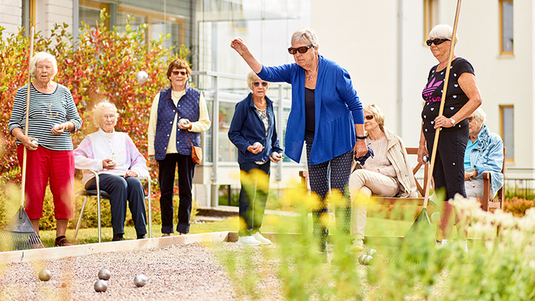 Pensionärer på Trygghetsboendet Skepparen umgås och spelar boule i solskenet. Foto.